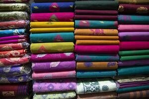 Variété artistique de couleurs de ton d'ombre saree's empilés sur l'étagère du magasin de détail à vendre photo