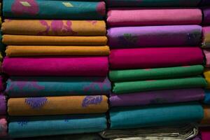 Variété artistique de couleurs de ton d'ombre saree's empilés sur l'étagère du magasin de détail à vendre photo