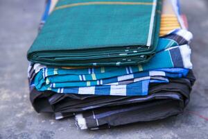 plié coton en tissu lungi sur foncé béton sol traditionnel Pour des hommes mode mode de vie dans Bangladesh. sélectif concentrer photo