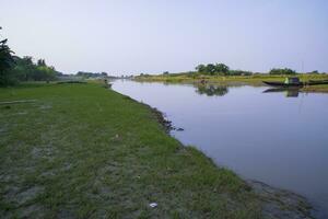 canal avec vert herbe et végétation réfléchi dans le l'eau près padma rivière dans bangladesh photo