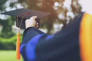 l'obtention du diplôme, l'étudiant tient le chapeau à la main pendant le début de la réussite des diplômés de l'université, l'éducation conceptuelle félicitation. cérémonie de remise des diplômes, a félicité les diplômés de l'université. photo