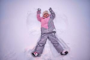 une fille fait du une neige ange dans blanc neige dans l'hiver. photo