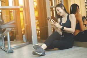 asiatique femme en jouant mobile téléphone avec social médias. à salle de sport. photo