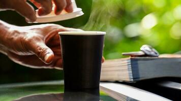 café à emporter dans une papier tasse sur Haut de le voiture toit vert arbre Contexte à lever du soleil dans le matin, sélectif se concentrer, doux se concentrer. photo