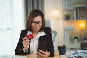 femme d'affaires en portant crédit carte et en utilisant portable ordinateur à achats en ligne. femme d'affaires travail à maison. en ligne achats, commerce électronique, l'Internet bancaire, dépenses argent, achats de partout. photo