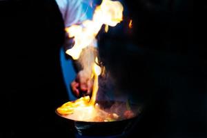 chef cuisinier avec flamme dans une poêle à frire sur une cuisinière photo