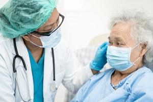 un médecin asiatique aide une patiente asiatique âgée dans un hôpital de soins infirmiers. photo