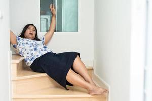 une femme asiatique tombe dans les escaliers à cause des surfaces glissantes photo
