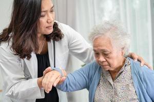 aider et soigner une patiente asiatique âgée assise sur un fauteuil roulant photo