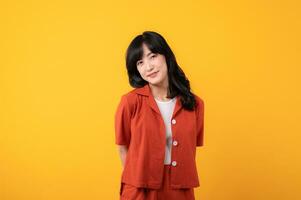 portrait Jeune magnifique asiatique femme content sourire habillé dans Orange vêtements isolé sur Jaune studio Contexte. asiatique fille Humain affronter. photo