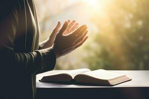 mains ensemble dans prier à Dieu le long de avec le saint Bible livre photo