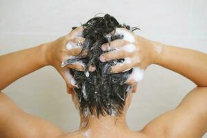 une homme est la lessive le sien cheveux avec shampooing photo