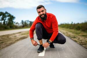 Jeune homme est attacher une lacet avant jogging. photo