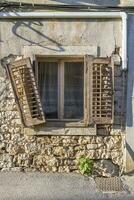 image de un vieux fenêtre avec une endommagé obturateur dans un vieux pierre maison photo