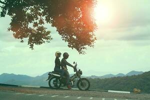 des couples portant sécurité casque séance sur petit enduro moto contre magnifique Naturel Montagne scène à Khaoyai nationale parc Thaïlande photo