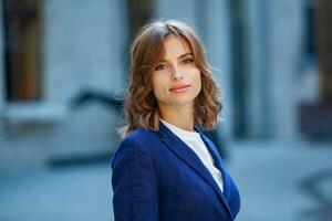 portrait de une réussi affaires femme dans de face de moderne affaires bâtiment. Jeune directeur pose dehors. femme employé de un bureau. photo