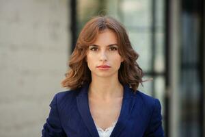 portrait de une réussi affaires femme dans de face de moderne affaires bâtiment. Jeune directeur pose dehors. femme employé de un bureau. photo