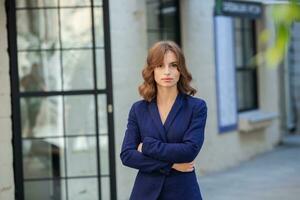 portrait de une réussi affaires femme dans de face de moderne affaires bâtiment. Jeune directeur pose dehors. femme employé de un bureau. photo