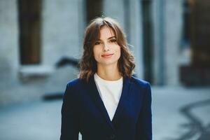 portrait de une réussi affaires femme dans de face de moderne affaires bâtiment. Jeune directeur pose dehors. femme employé de un bureau. photo