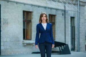 portrait de une réussi affaires femme dans de face de moderne affaires bâtiment. Jeune directeur pose dehors. femme employé de un bureau. photo