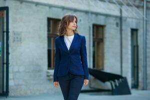 portrait de une réussi affaires femme dans de face de moderne affaires bâtiment. Jeune directeur pose dehors. femme employé de un bureau. photo