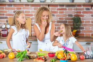 mère et filles cuisine ensemble dans le cuisine. en bonne santé nourriture concept. portrait de content famille avec Frais smoothies. content sœurs. photo