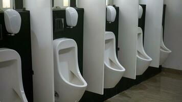 le intérieur de le toilette consiste de une blanc céramique urinoir et savon plat dans le Hôtel avec une céramique sol. nettoyer Hommes toilette photo