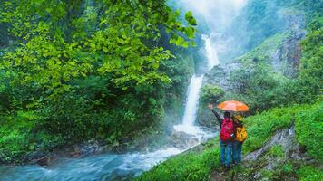 amoureux asiatique homme et asiatique femmes Voyage la nature Voyage le le plus élevé cascade dans chiangmai mae-pan cascade pluvieux saison à est ce que je intanon. photo