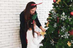 La mère et l'enfant asiatiques décorent ensemble l'arbre de Noël photo