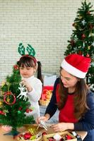 La mère et l'enfant asiatiques décorent ensemble l'arbre de Noël photo