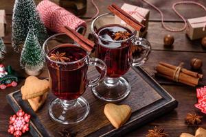 vin rouge chaud de noël avec des épices et des fruits sur une table sombre. photo