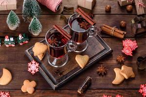 vin rouge chaud de noël avec des épices et des fruits sur une table sombre. photo