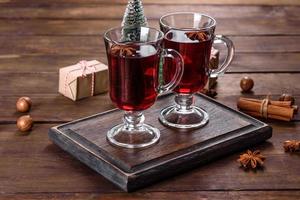 vin rouge chaud de noël avec des épices et des fruits sur une table sombre. photo