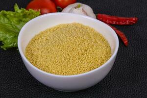 couscous cru dans le bol servi feuilles de salade, tomate et poivron photo