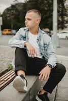 Urbain contemplation. Jeune homme dans denim veste Profond dans pensée. ville rêver. maussade Jeune gars dans élégant denim veste. réfléchi citadin. Jeune homme reflétant dans le sien denim veste photo