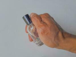 une homme main élégamment détient une verre parfum bouteille sur une blanc Contexte photo