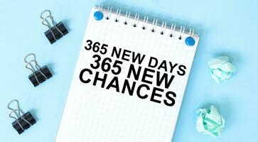 blanc bloc-notes avec texte 365 Nouveau journées 365 Nouveau chances et Bureau outils sur le bleu Contexte photo