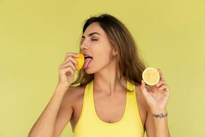 magnifique femme posant plus de vert Contexte , en portant Frais citrons. beauté studio portrait. en bonne santé la vie style. photo