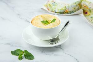 tasse de café avec mousse et une brin de menthe sur une marbre Contexte photo