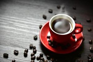 tasse de café rouge avec vapeur de flux et grain de café photo