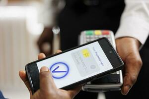 proche en haut de Humain main en portant téléphone intelligent en utilisant mobile nfc Paiement tandis que payant pour Hôtel prestations de service, sans contact pos paiement. gens en utilisant bancaire app à Payer via nfc technologie, mobile portefeuille photo