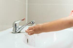 peu enfant mains laver avec savon bulles et rincer avec nettoyer l'eau à prévenir et Arrêtez le propager de germes après retour à maison, virus ou COVID-19 [feminine. bien santé et bien personnel hygiène, virus, les bactéries photo