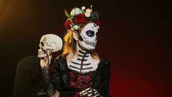 Père Noël muerte modèle agissant affectueux avec crâne et noir des roses, portant traditionnel corps art à célébrer mexicain vacances. à la recherche comme déesse de décès sur saint dios de los muertos rituel. ordinateur de poche tir. photo