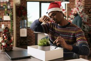 triste homme dans Père Noël chapeau rassemblement personnel Bureau des choses de bureau après avoir mis à la porte sur Noël veille. dérangé Commencez entreprise employé déchargé de emploi pendant hiver saisonnier vacances photo