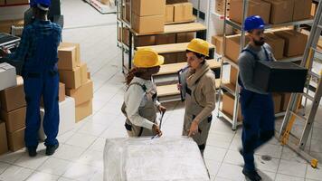 diverse femmes parlant à propos expédition et livraison dans espace de rangement chambre, en cours d'analyse liste de Stock logistique. Jeune gens travail avec industriel des produits et paquets de marchandises, magasin. trépied tir. photo