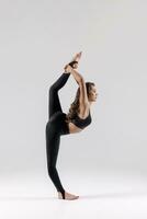 une magnifique mince gymnaste dans une étendue dans une survêtement Est-ce que des sports ou yoga dans le studio élongation photo