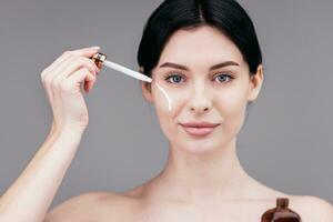 proche en haut de femme corps se soucier à maison. portrait de femme appliquant Crème hydratante crème sur cou. Naturel peau se soucier photo