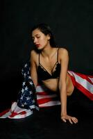 portrait femelle athlète enveloppé dans américain drapeau contre noir Contexte photo
