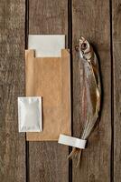 séché à l'air poisson-sabre avec kraft papier sac, humide essuyer et papier serviette de table sur en bois surface photo