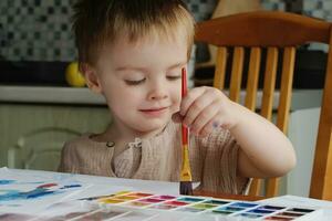 bambin Accueil loisirs. petit garçon en utilisant peindre à dessiner. photo